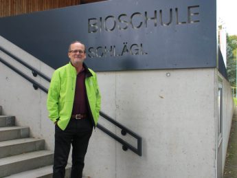 Direktor vor Schulschild